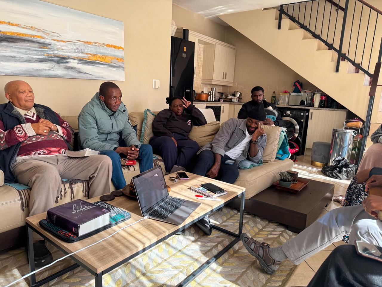 The household seated together in the lounge listening during a fellowship meeting